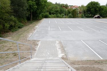 Přístupová cesta k parkovišti po schodišti, podélně vede bezbariérová rampa